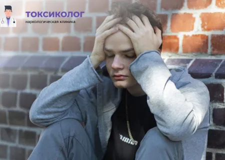 Подросток в капюшоне сидит, держась за голову от боли, Лечение токсикомании.